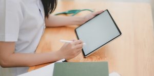 Cropped shot of young female doctor examining the patient chart while using tablet